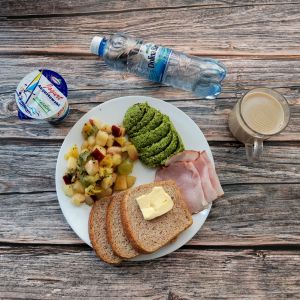 Zdjęcie przedstawia Dietę z ograniczeniem łatwoprzyswajalnych węglowodanów: Chleb Graham Masło extra Sałatka owocowa Szynka krucha z pieca wieprzowa, parzona Kawa zbożowa z mlekiem Jogurt naturalny Woda mineralna Pasta z groszku zielonego